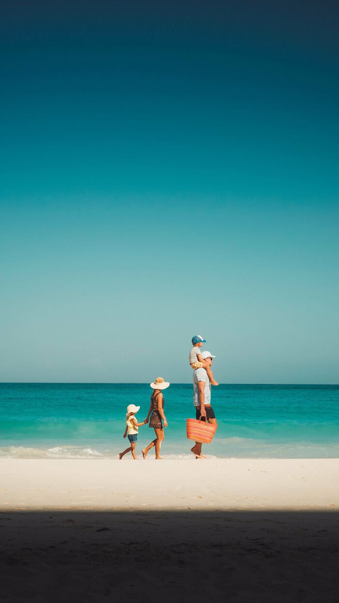 Family walking on a sunny beach, capturing creative street photography moments by the ocean.