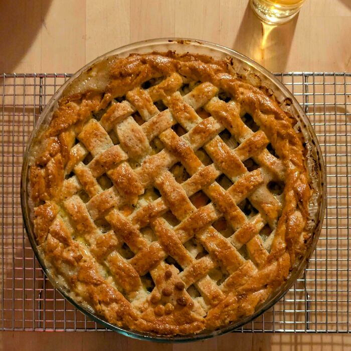 Golden lattice pie cooling on a rack, illustrating a baker's culinary skill taken to a whole other level.