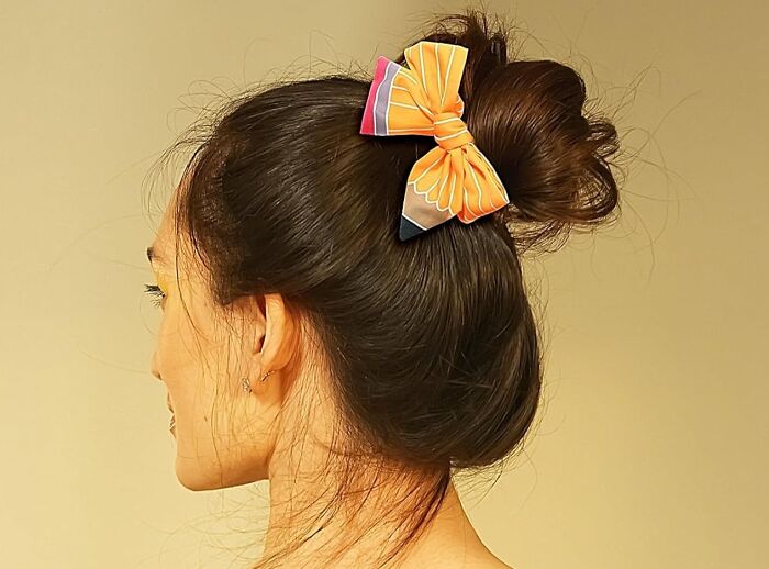 Woman with a bun hairstyle adorned by a vibrant orange bow, suitable as a thoughtful gift for teachers.