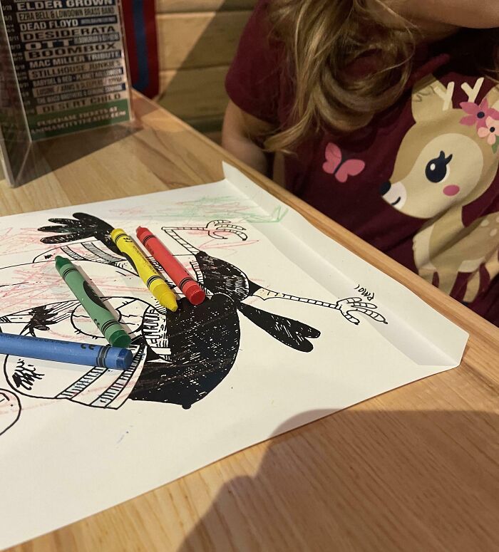 Child coloring a drawing with crayons, wearing a shirt with a deer design, showcasing parenting genius tricks.