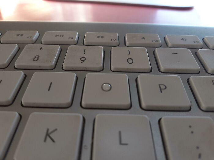 A small object perfectly fits between keyboard keys, illustrating a satisfying perfect fit.