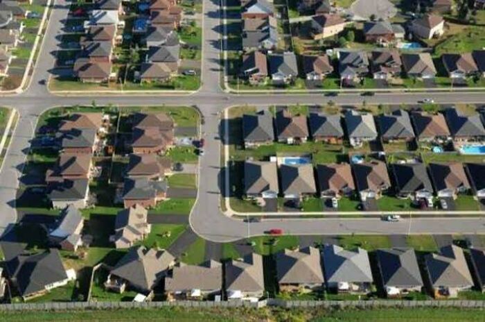 Aerial view of dense urban housing, showcasing uniform streets and identical homes, a depiction of urban hell.