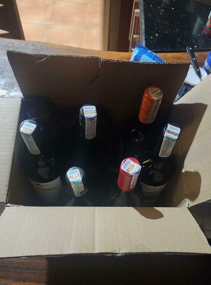 Cardboard box with assorted wine bottles, representing disappointing gifts.