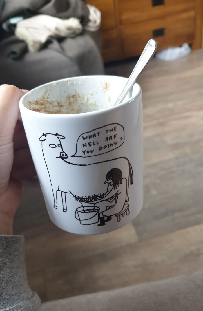 Hand holding a mug with a funny cow cartoon, perfect trolling Christmas gift idea.