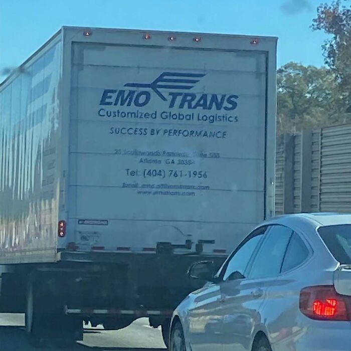 Truck with "Emo Trans" logo driving on a highway, highlighting weirdness with its unusual branding.