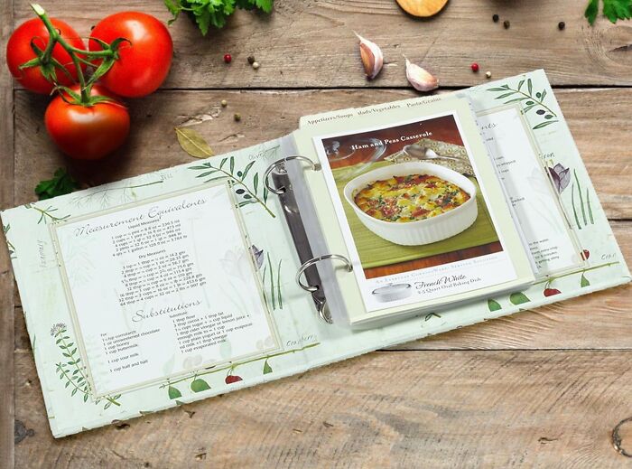 Recipe binder with casserole dish photo, fresh tomatoes, garlic, and herbs on wooden table for Christmas gifts