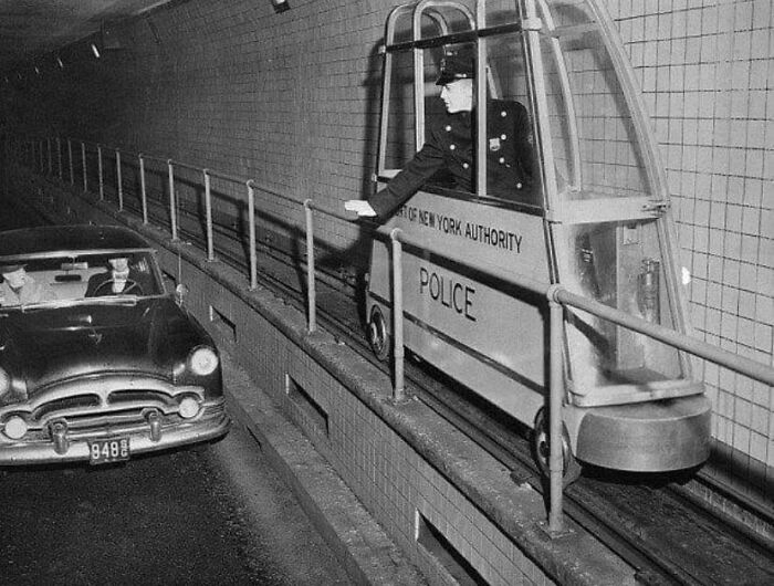 Police officer in strange invention vehicle beside car in tunnel.