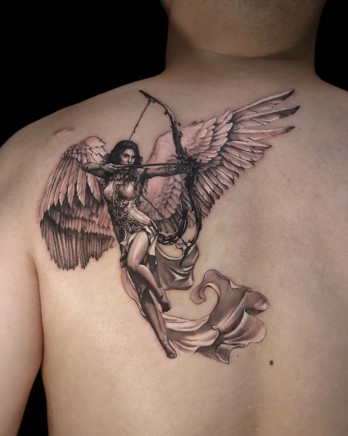 Realistic tattoo of a winged female archer on a person's back, showcasing mastery in tattoo art realism.