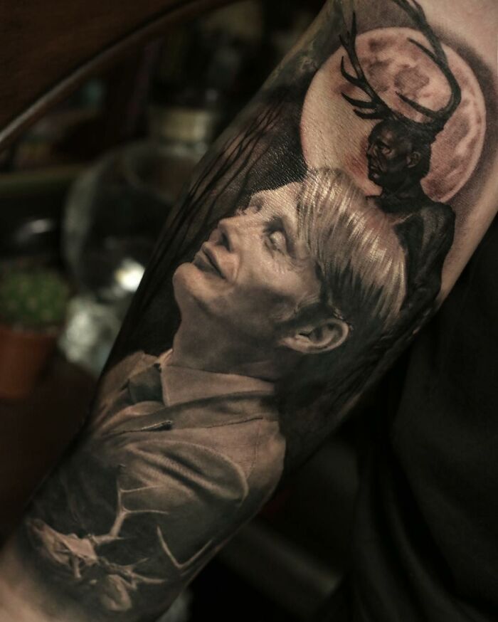 Realistic tattoo depicting a contemplative figure under a full moon with antlers, showcasing mastery in realism.