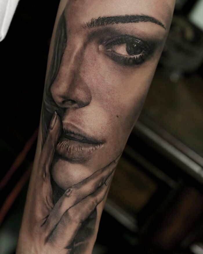 Realism tattoo art depicting a woman's face and hand in detailed grayscale style.