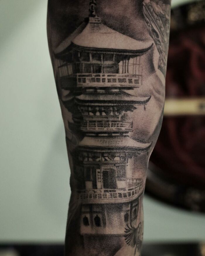 Realistic tattoo art of a detailed pagoda on an arm, showcasing mastery in ink and illusion.