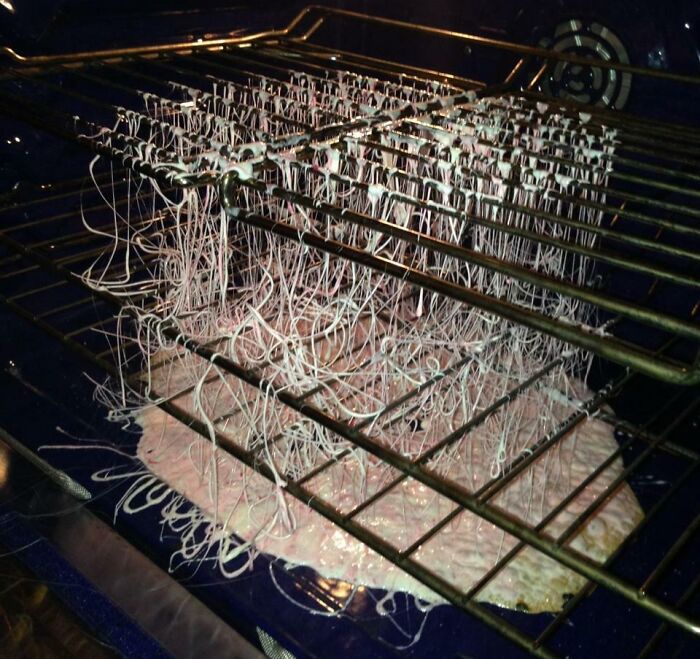 Failed Christmas pizza in oven, melted onto rack creating a messy accident.