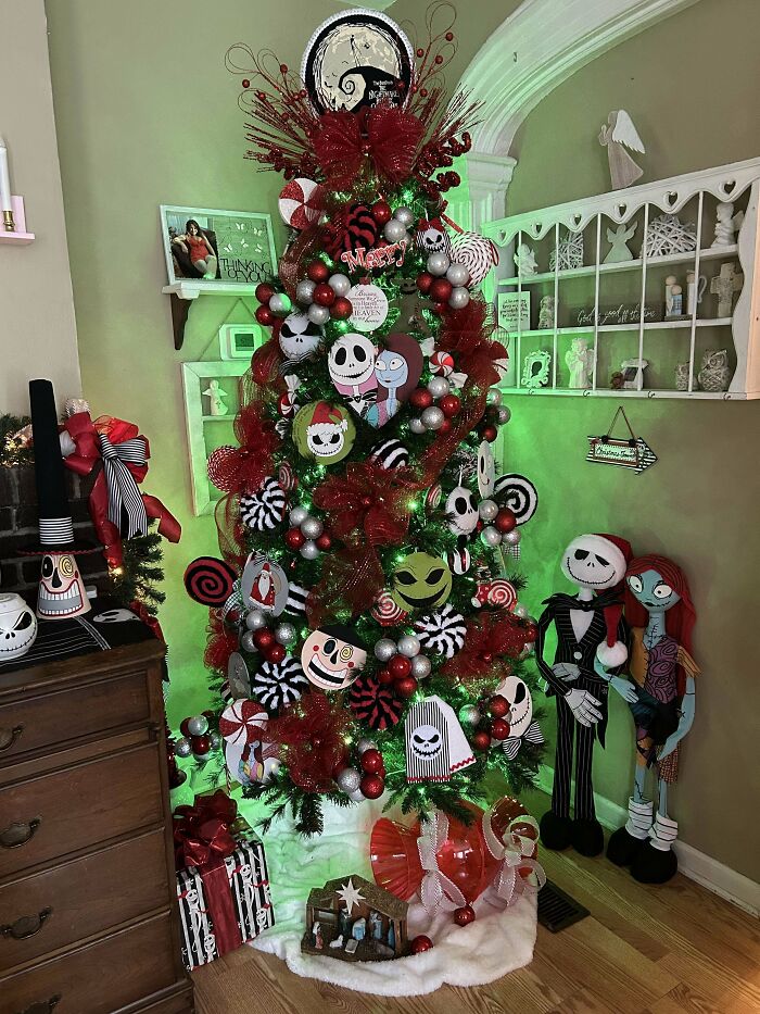Nightmare Before Christmas themed tree with red and green decorations, featuring characters as ornaments, next to wrapped gifts.