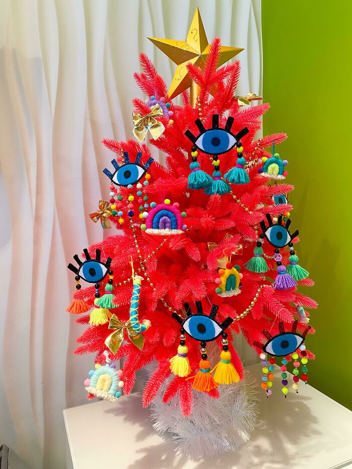 Vibrant red Christmas tree adorned with colorful, eye-themed ornaments and a golden star.