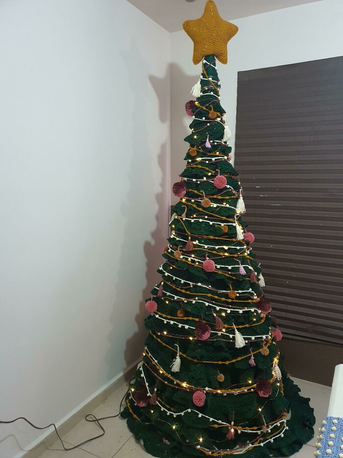 Decorative Christmas tree with lights, pom-poms, and a large star topper, showcasing a creative holiday design idea.