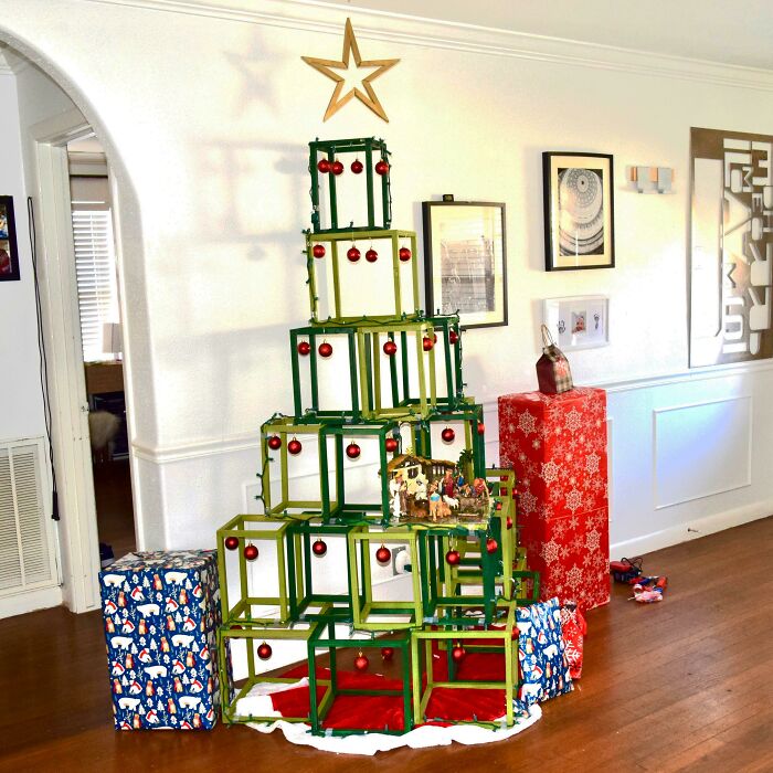 Creative Christmas tree idea using stacked green frames with red ornaments and a star topper, surrounded by wrapped gifts.