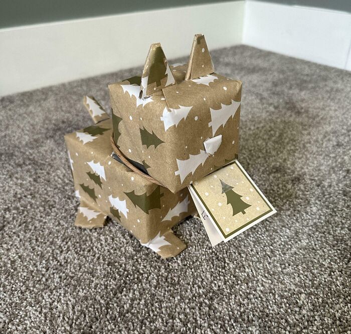 Origami gift shaped like a dog, wrapped in Christmas paper with trees, part of hilarious trolling Christmas gifts.