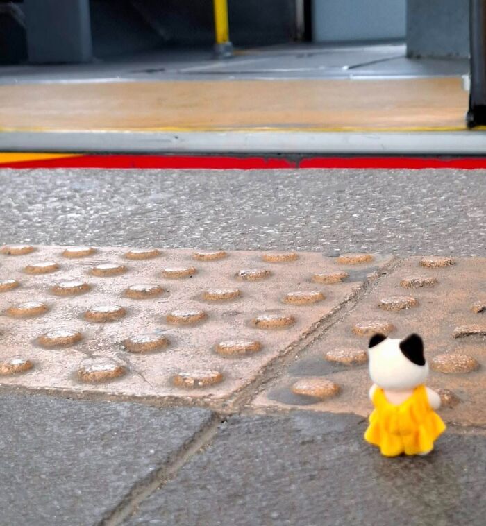 Toy figurine in a yellow dress on a bumpy sidewalk, highlighting bizarre social media post.