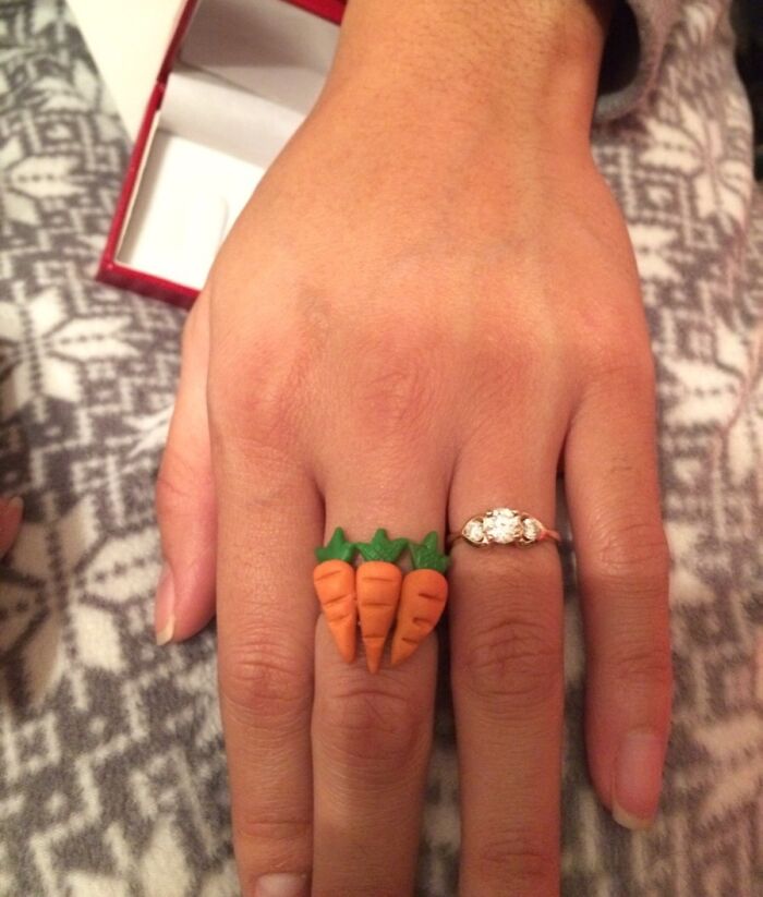 Hand wearing a carrot-themed ring and a diamond ring, showcasing trolling Christmas gift humor.