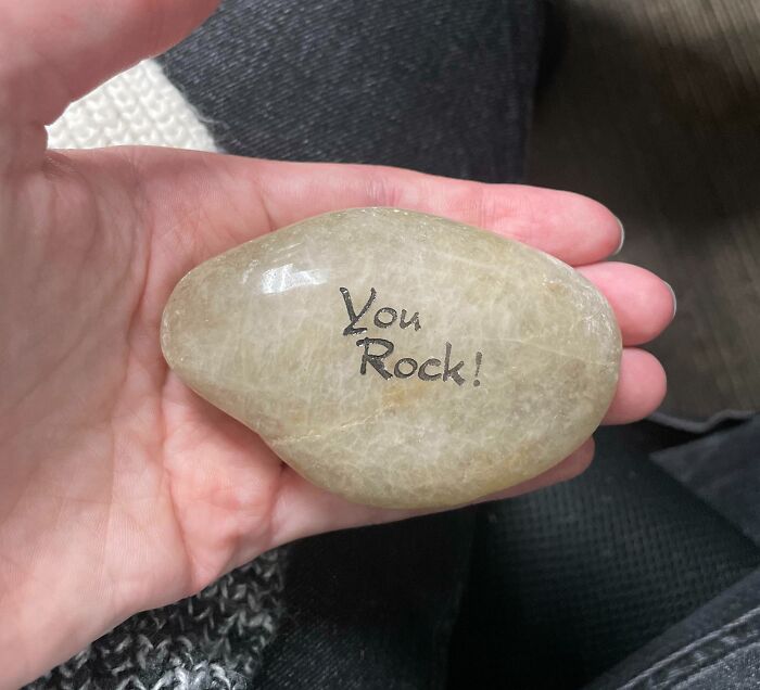 Hand holding a rock with "You Rock!" text, symbolizing disappointing presents.