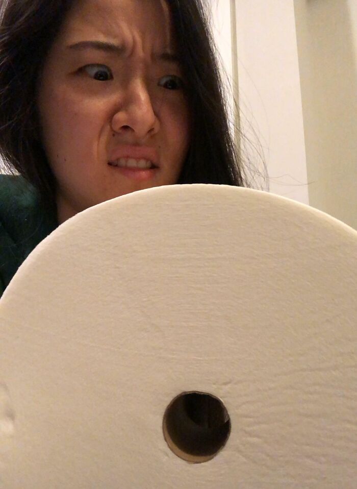 A woman making a funny face at a giant roll of toilet paper, featuring a gift from trolling Christmas gifts.