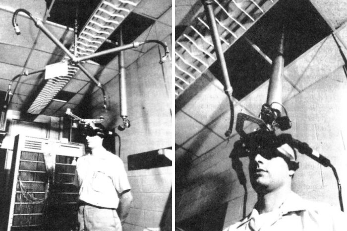Person using a strange invention device attached to the ceiling, featuring headgear and metal rods in a grayscale room.