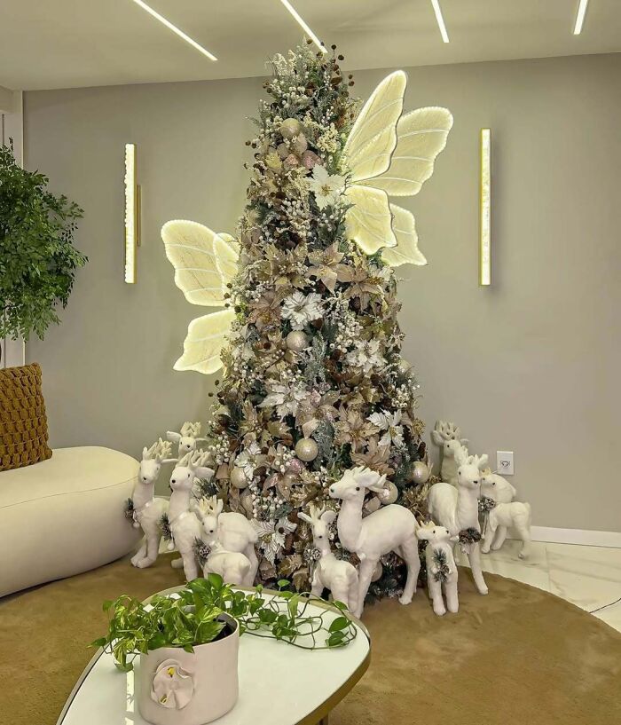 Christmas tree decorated with fairy lights and surrounded by white reindeer figures.