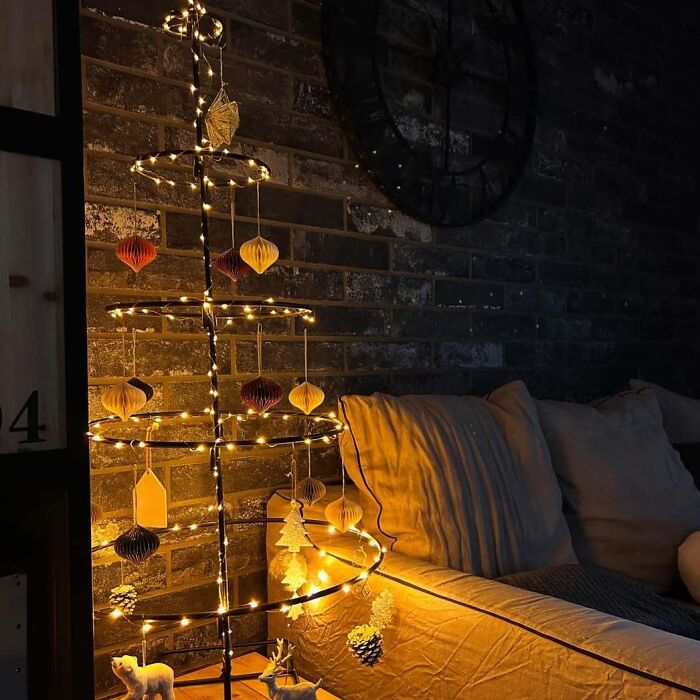 Minimalist Christmas tree idea with glowing lights and paper ornaments in a cozy living room setting.