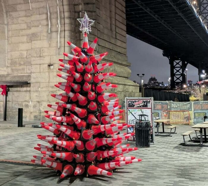 Creative Christmas tree idea made from stacked traffic cones under a bridge at night.