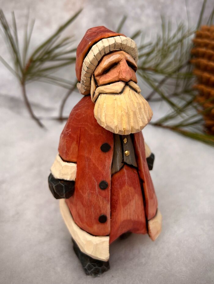 Hand-carved Santa figurine displaying creative DIY Christmas decorations with pine branches in the background.