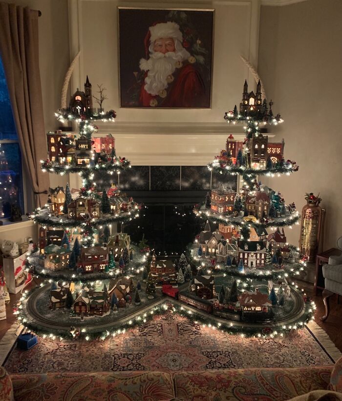 Christmas tree idea with village display, sparkling lights, and a Santa portrait above a cozy room setting.
