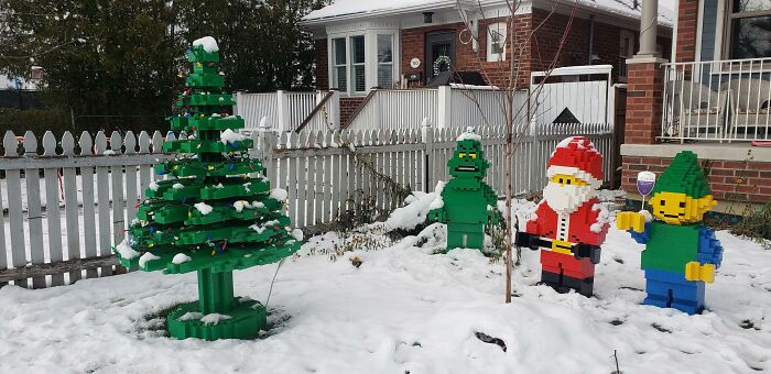 LEGO Christmas tree and characters in snowy yard near picket fence for creative decoration ideas.