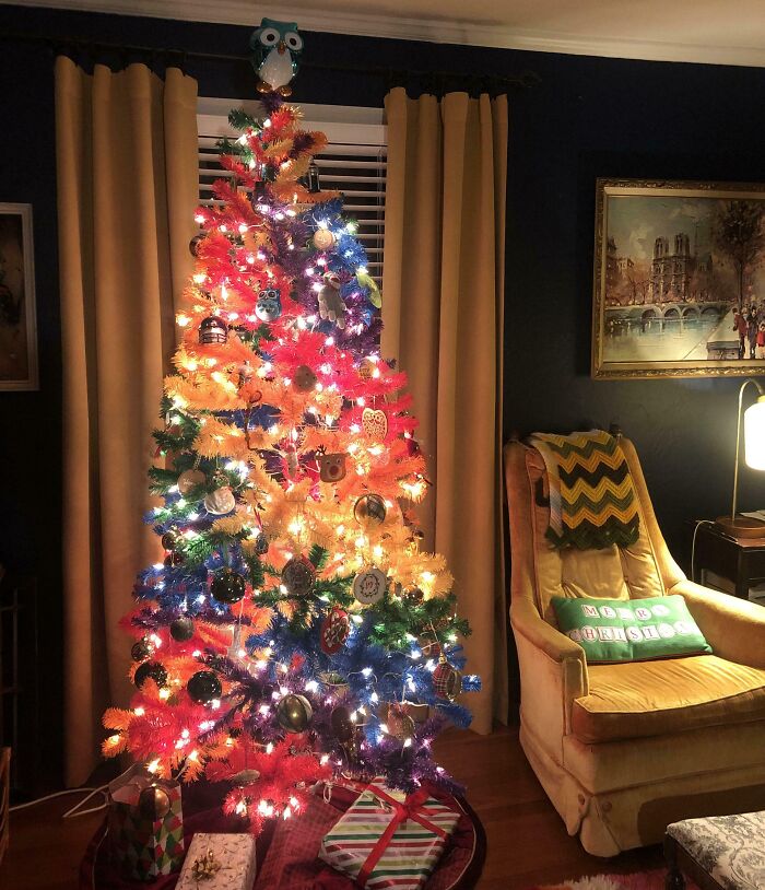 Colorful Christmas tree with multicolored lights and ornaments in a cozy living room setting.