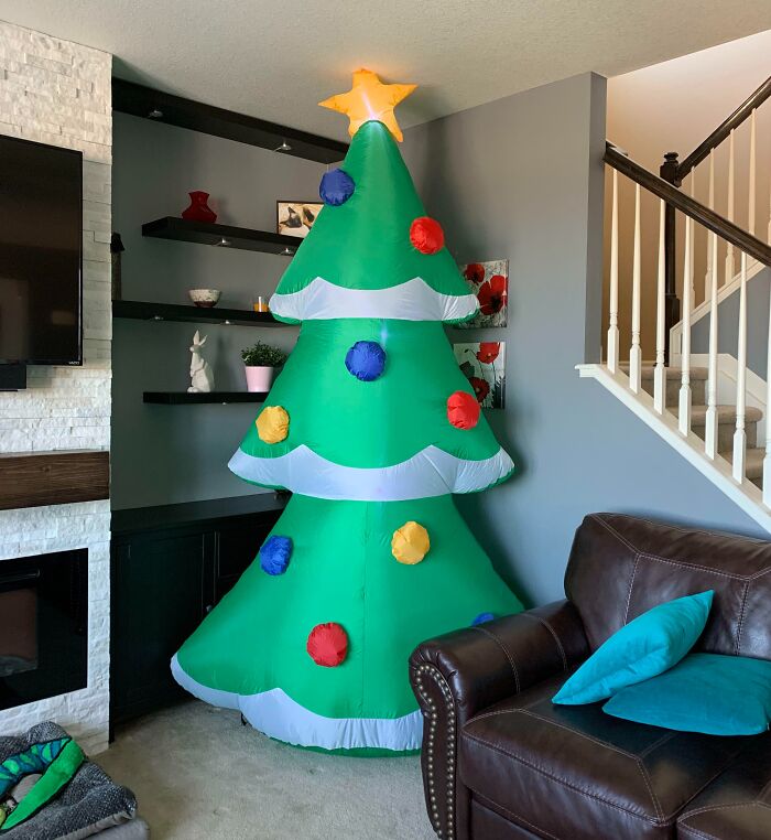 Inflatable Christmas tree with colorful decorations in a living room corner, enhancing holiday cheer.