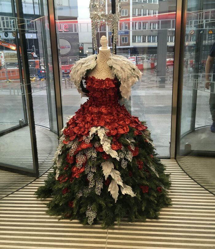 Dress-shaped Christmas tree decorated with red and white foliage, displayed indoors.