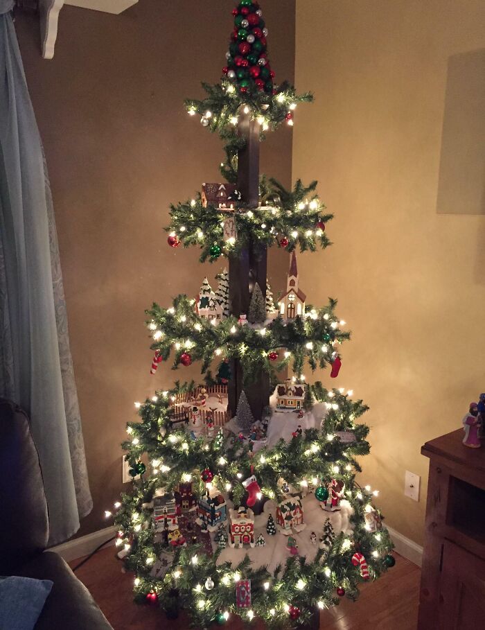 Unique Christmas tree idea with illuminated village decorations and festive ornaments.