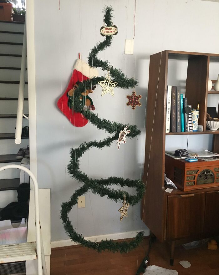 Minimalist Christmas tree idea with spiral garland, ornaments, and a stocking, hanging creatively in a living room.