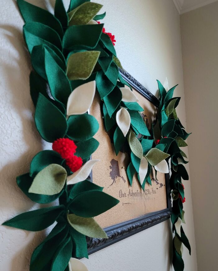 Creative DIY Christmas decorations made of felt leaves and berries hanging on a picture frame.