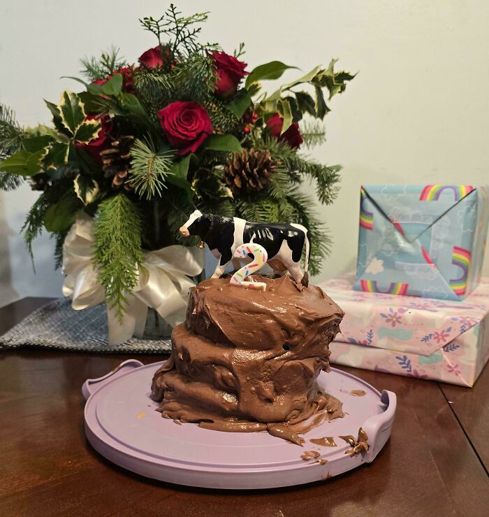 Creative baking with a cow-topped chocolate cake, floral arrangement, and wrapped gifts.