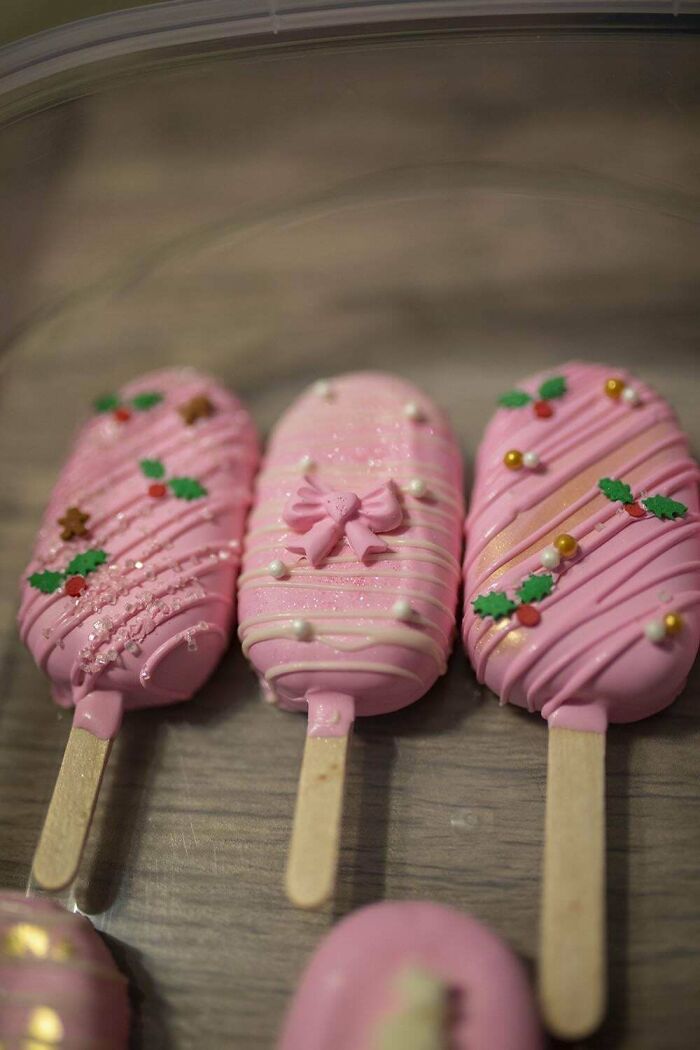 Pink cake popsicles with festive decorations, showcasing bakers' culinary creations.