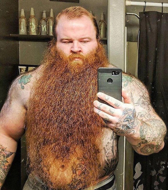 Heavily tattooed man with an enormous beard taking a selfie, representing absolute-units-things.