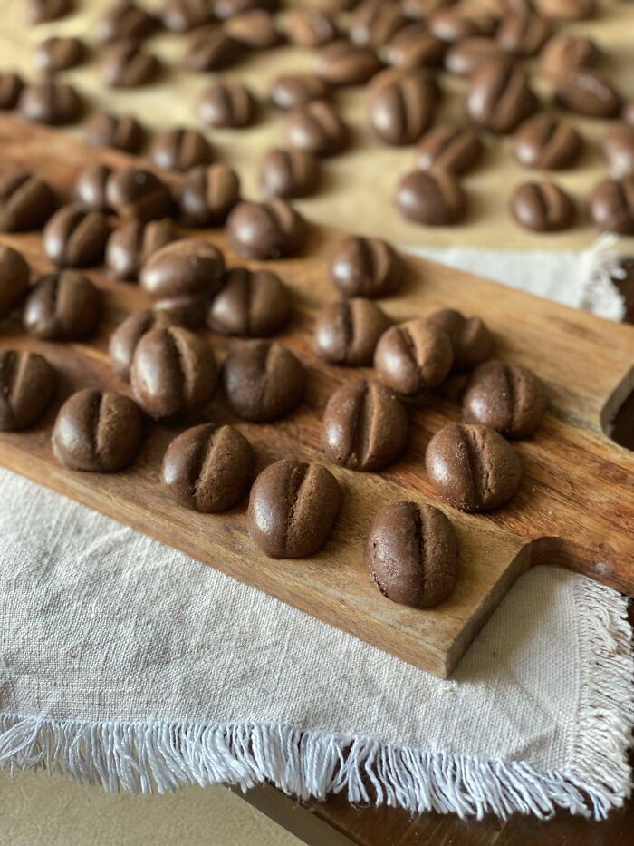 Creative chocolate cookies shaped like coffee beans on a wooden board, showcasing unique baked culinary concoctions.