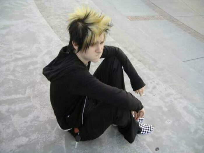 Person in black outfit and spiky hair sitting on steps, reflecting on their "blunder years."