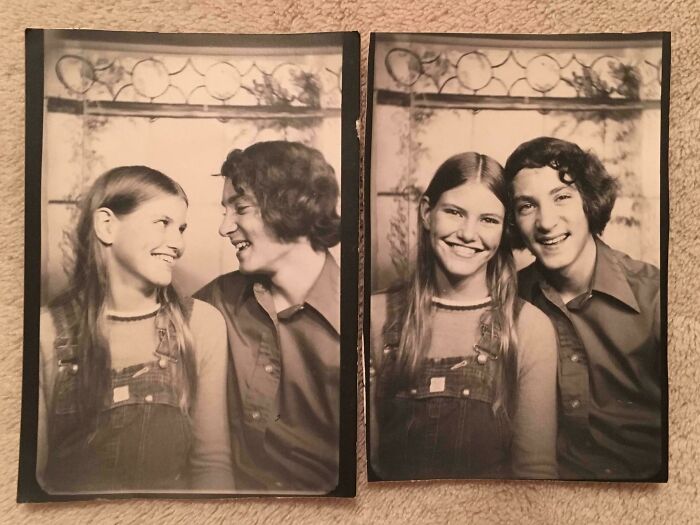 Smiling teenagers in '70s high school fashion, wearing denim overalls and collared shirts, in a vintage black-and-white photo booth.