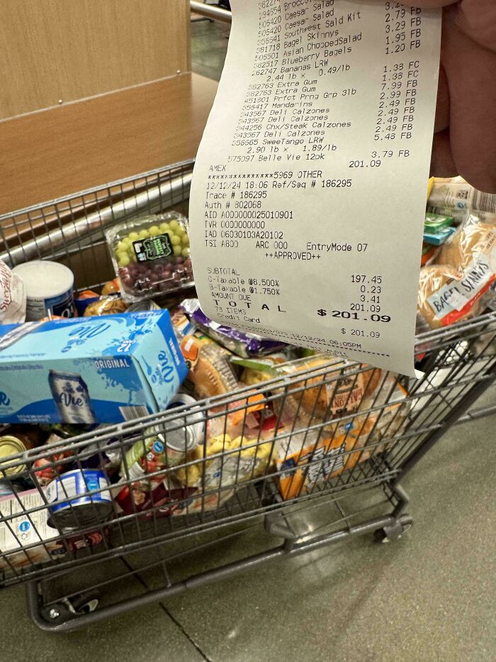 Shopping cart filled with groceries, held receipt totals $201.09, showcasing the rewarding job of being a dad.