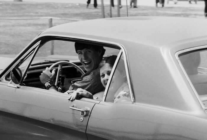 Two high school students from the '70s smiling in a vintage car.