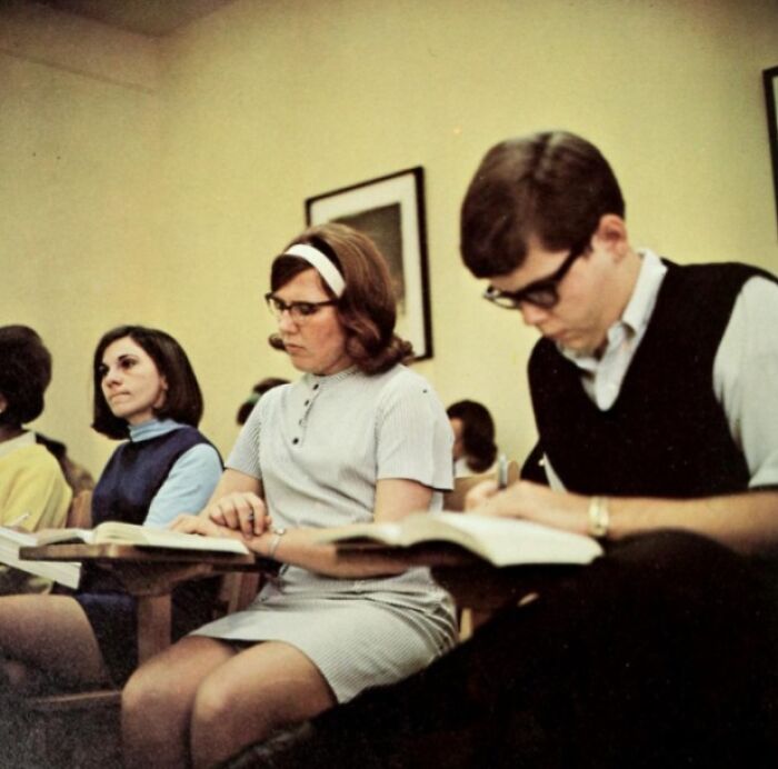 Students in a 1970s high school classroom taking notes, highlighting vintage educational style and fashion.