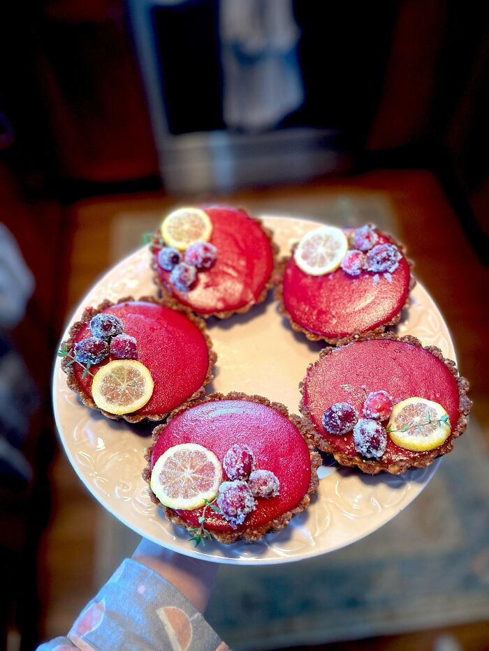 Plate of vibrant red tarts with lemon slices and berries, showcasing bakers' exceptional culinary concoctions.