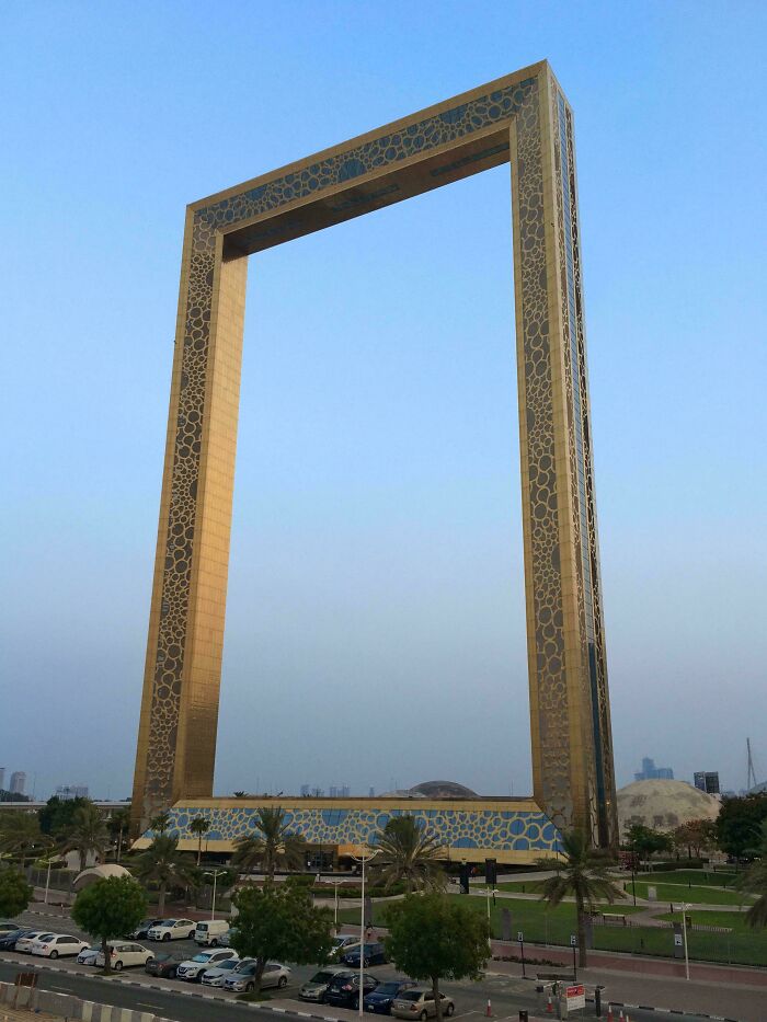 Golden architectural frame in an urban setting under a clear blue sky.
