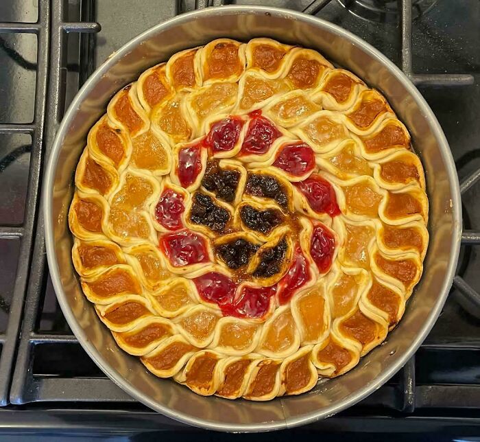 Colorful, intricate pie design showcasing bakers' culinary creativity on a stovetop, featuring swirled fruit fillings.